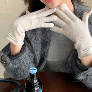 Detail of off-white knit gloves featuring 100% wool material and a rolled cuff design