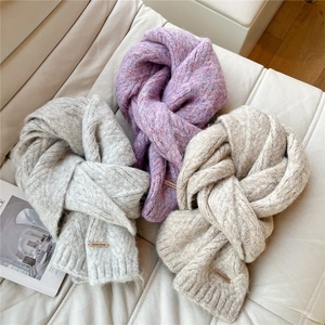 Close-up of thick knit winter scarves in grey and pink showing soft texture and metal tag