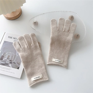 Detail of 100% wool knit glove label with textured oatmeal fabric on white background