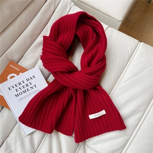Close-up of red 100% wool knitted scarf with thick rib texture on a white leather sofa
