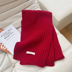 Close-up of 100% wool label on thick burgundy ribbed knit scarf for winter warmth