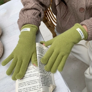 Detail of green 100% wool knitted gloves showing thick texture and wool material label
