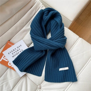 Detailed close-up of dark blue 100% wool knit scarf with premium ribbed texture and label