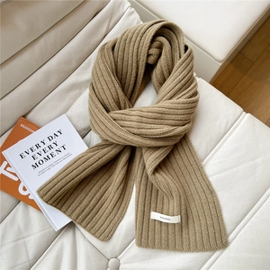 Detailed view of camel 100% wool knitted scarf with rib pattern and white composition label