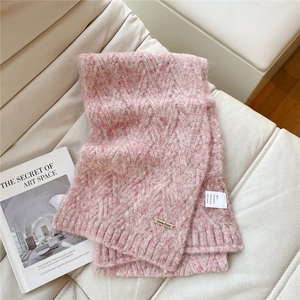 Close-up of pink cable knit scarf with wool blend texture on a leather sofa