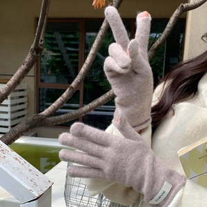 Detailed view of 100% wool knitted gloves featuring high-quality texture and fabric label