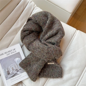 Close-up of thick multicolored knit winter scarf with engraved gold metal brand logo