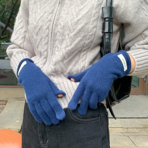 Close-up of 100% wool knit gloves in navy blue worn by a model in outdoor setting