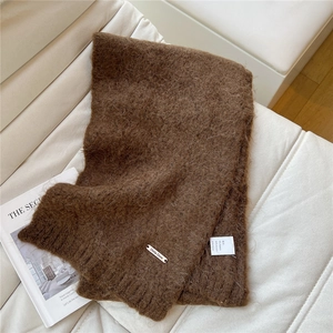 Detail of brown knitted scarf with soft fuzzy texture and Doria Dore metal logo