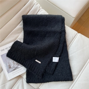 Detail of knit scarf texture with alpaca wool blend fabric and metal logo plate