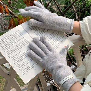 Detail of wool knit gloves with white logo label shown in cozy winter outdoor setting