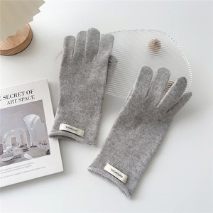 Detail of light gray 100% wool knitted gloves showing the authentic fabric texture and label