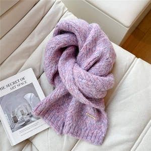 Close-up of thick chunky knit scarf in purple and pink with gold brand logo plate