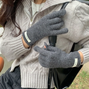 Detail of dark grey 100% wool knitted gloves featuring a white branded wrist label