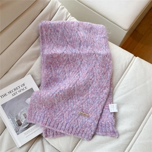 Detail of chunky cable knit texture on pink and purple scarf with metal brand tag