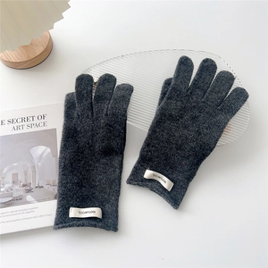 Detailed view of dark grey 100% wool knitted gloves with white fabric label and soft texture