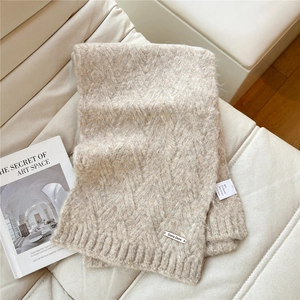 Detail of beige knit scarf with Alpaca wool blend texture and metallic brand logo