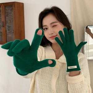 Detail of green knitted gloves showing 100% wool material label and warm texture