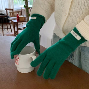 Detail of 100% wool green knitted glove cuff with label on winter warm winter accessories