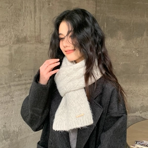 Close-up of white knitted scarf texture with Doria Dore label on black wool coat