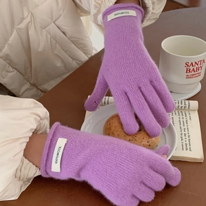Detail of purple knitted wool gloves with 100% wool label on cozy wooden background