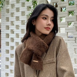 Detail of dark brown plush scarf with a gold metallic logo tag for winter style