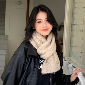 Close-up of beige chunky knit scarf with cable pattern texture on a fashion model