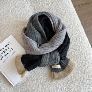 Détail de l'écharpe en maille bicolore grise avec bordure en fausse fourrure sur tapis