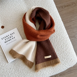 Détail d'une écharpe en maille côtelée tricolore avec patchwork blanc, orange et brun