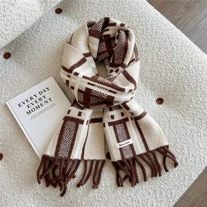 Detail of soft brown and beige plaid knitted scarf with fringes on white fleece