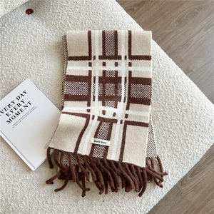 Close-up of brown and beige striped knit scarf with tassels and brand woven label