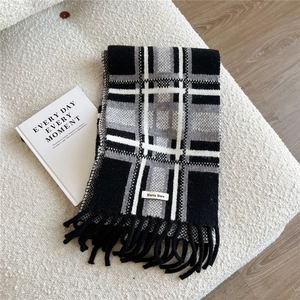 Close-up of black and grey striped knit scarf with long tassels and branded woven label