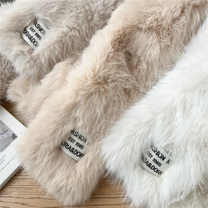 Detailed view of plush faux fur scarves in beige, brown, and white on a wooden surface