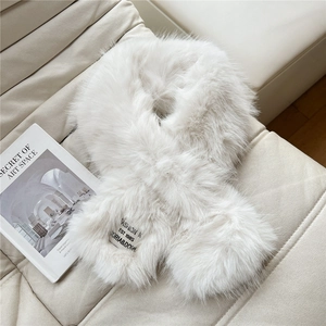 Detail of white faux fur cross scarf featuring a minimalist black fashion label and soft texture