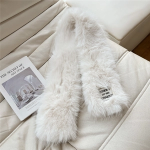 Close-up of plush cream faux fur scarf texture with a stylish fashion woven label