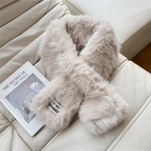 Close-up of fluffy beige faux fur scarf with a minimalist brand label on soft texture