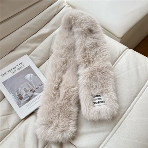 Detail of soft cream faux fur scarf texture and minimalist rectangular fabric label