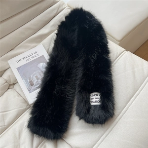 Close-up of plush black faux fur scarf with brand label on a stylish cream sofa