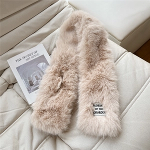 Detail of soft beige faux fur scarf texture with decorative woven label on leather sofa