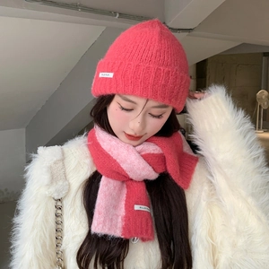 Detail of warm pink knitted beanie and striped scarf set with woven ELLDI PLAN labels