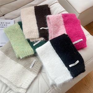 Flat lay of colorful thick knit scarves with soft fuzzy texture and woven brand labels