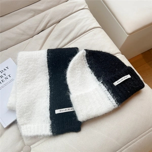 Close-up of black and white knit scarf and hat set with soft plush texture