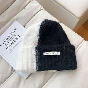 Close-up of black and white bicolor knit beanie with soft mohair texture and logo patch
