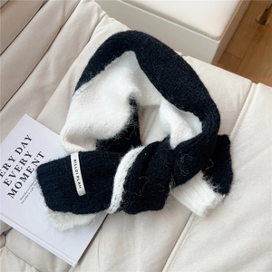 Close-up of soft black and white knit scarf texture with a stitched brand logo label