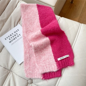 Close-up of pink and magenta knitted scarf texture with soft fibers and logo patch