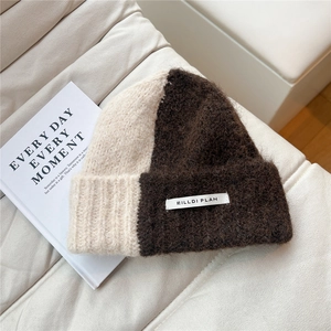 Close-up of two-tone beige and coffee knit beanie with woven brand label detail
