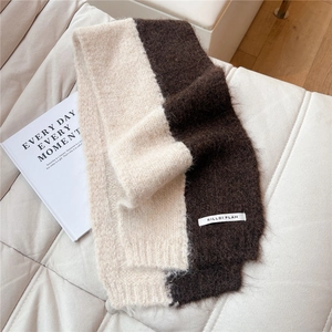 Detail of two-tone cream and brown knit scarf with plush mohair texture on a chair