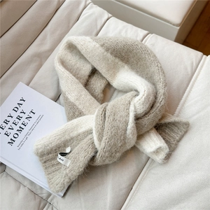 Macro detail of beige chunky knit scarf showing thick wool texture and brand label