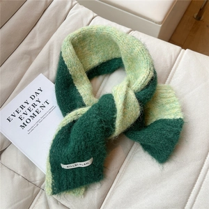Detail view of bicolor green knit scarf showing fluffy texture and brand label