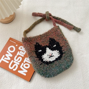 Détail du sac tricoté avec motif de chat tissé sur un fond chaud texturé